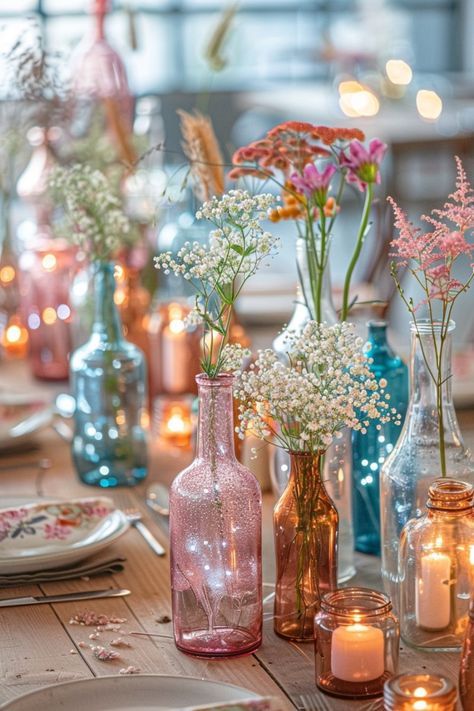 there are many different vases with flowers in them on the dining room table set for dinner