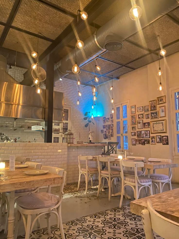 the inside of a restaurant with tables, chairs and lights hanging from the ceiling above