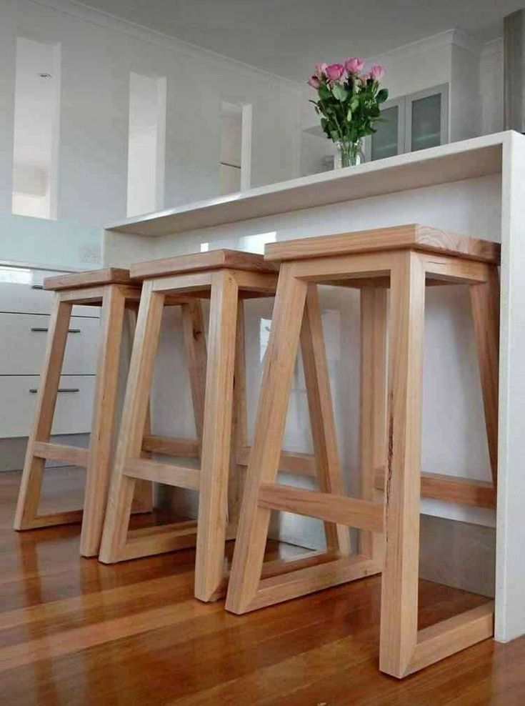 three wooden stools sitting on top of a hard wood floor next to a counter