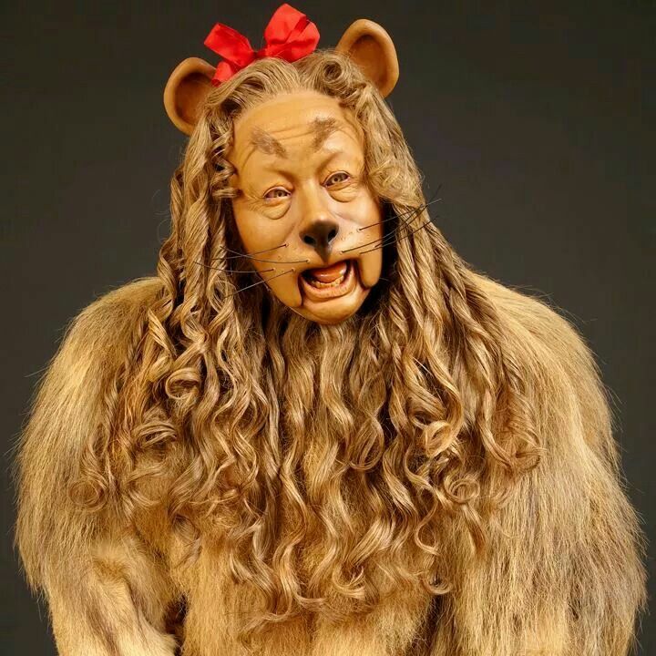 a man in a lion costume with long hair and a red bow on his head