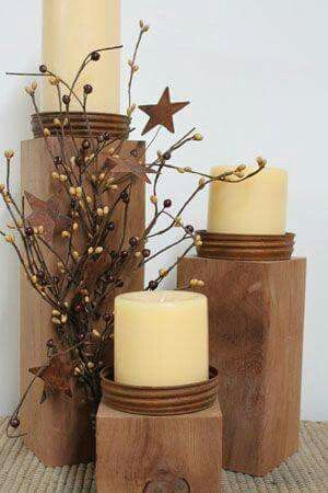 three candles are sitting next to each other on a wooden stand with branches and berries