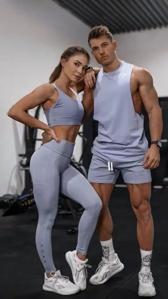 a man and woman standing next to each other in the gym with their hands on their hips