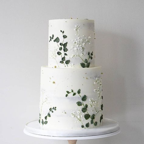 a three tiered cake with white flowers and green leaves