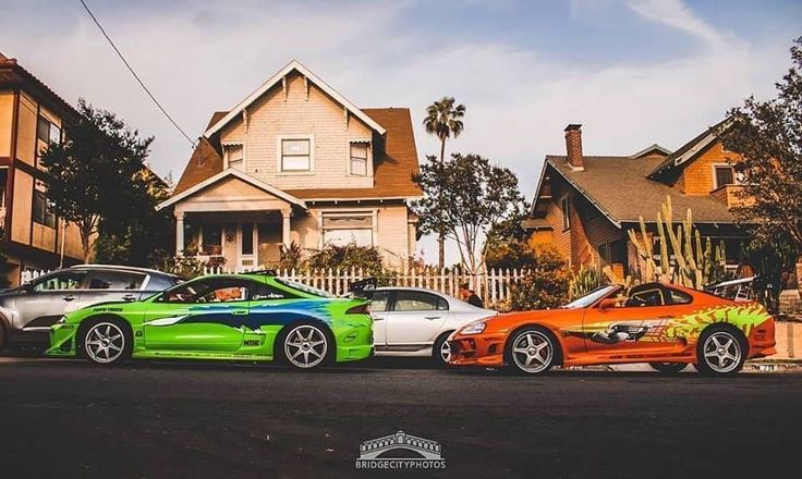 three different colored cars parked in front of houses