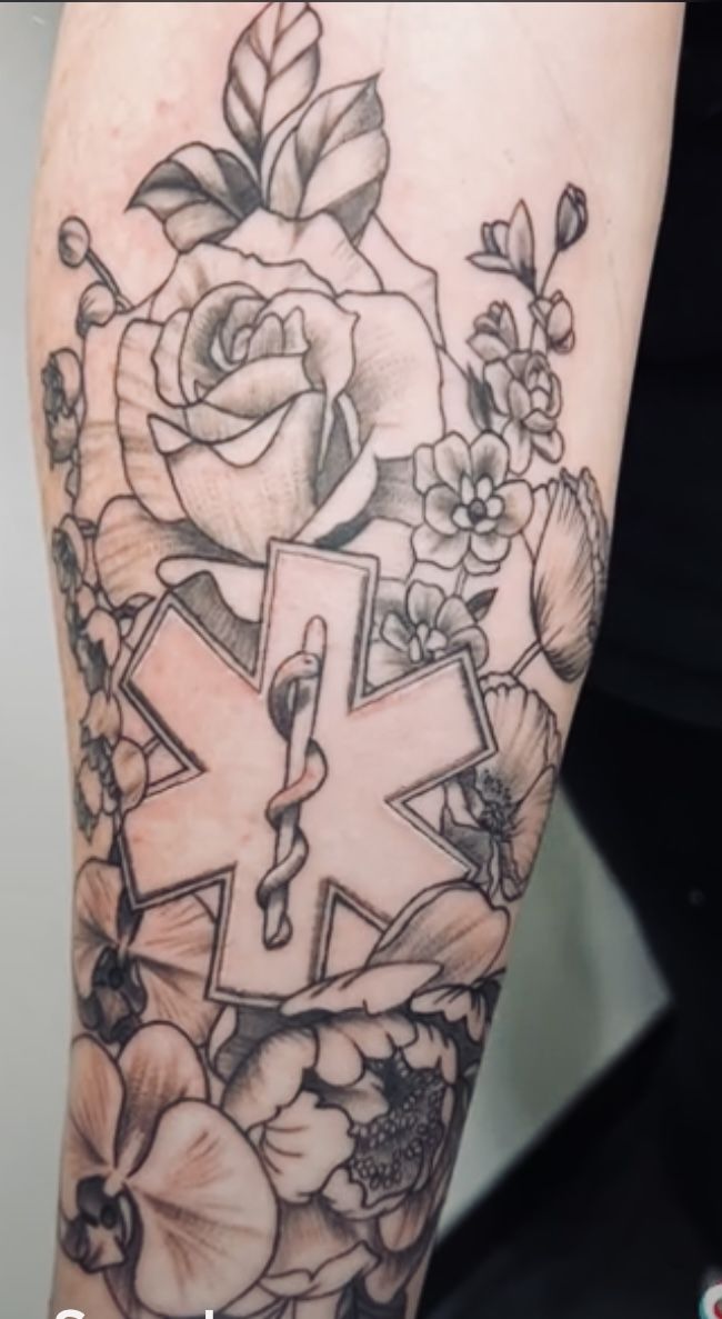 a woman's arm with flowers and a cross tattoo on the side of her leg