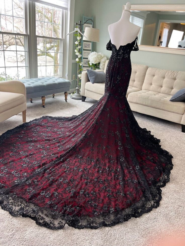 a black and red dress on display in front of a couch with a mirror behind it