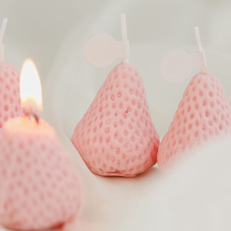 three pink candles sitting next to each other on top of a white surface with polka dots