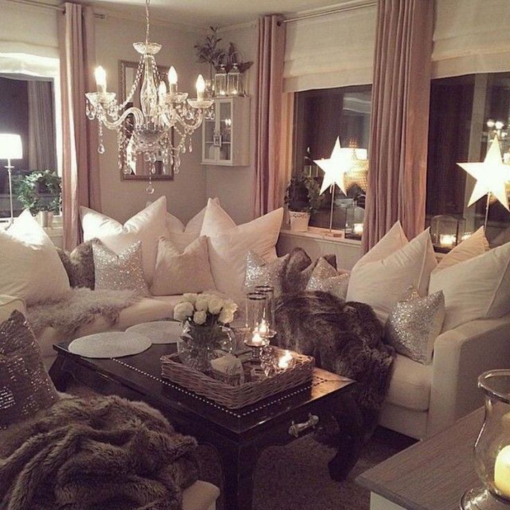 a living room filled with lots of white furniture and chandelier hanging from the ceiling