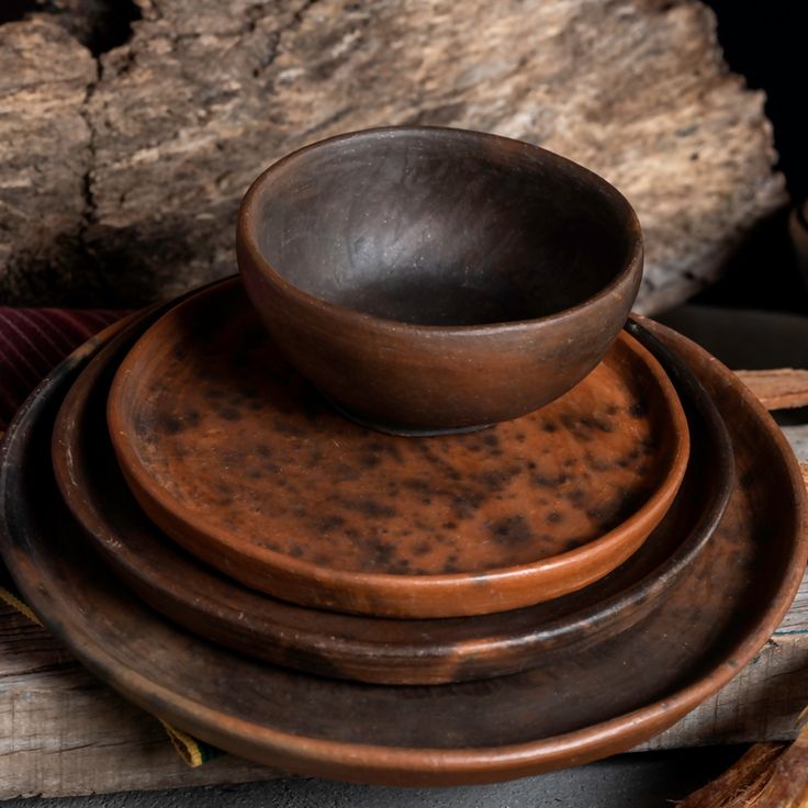 a wooden bowl sitting on top of three plates