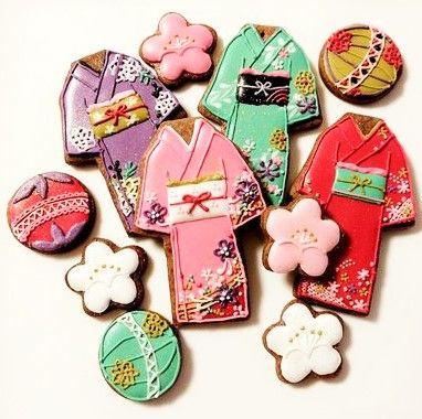 decorated cookies in the shape of geisha's and kimonos on a white surface