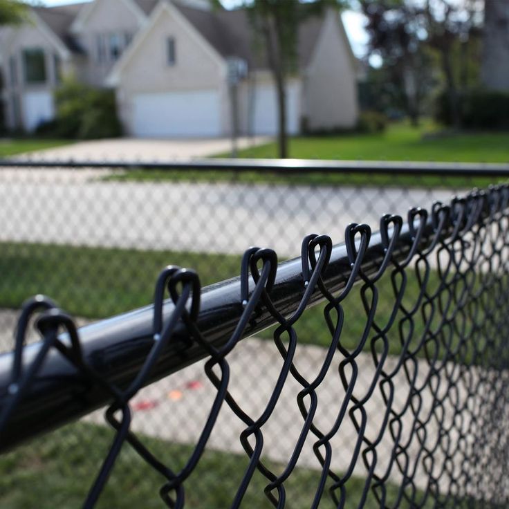 a chain link fence in front of a house with houses in the backround