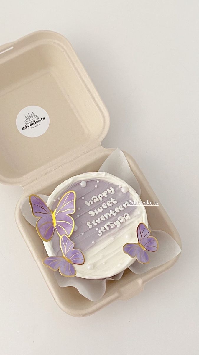 a birthday cake with purple butterflies on it in a plastic container that says happy mother's day