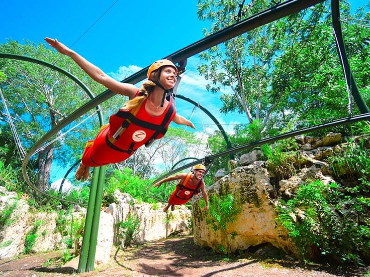 a woman is suspended in the air on a zip line with trees and rocks behind her