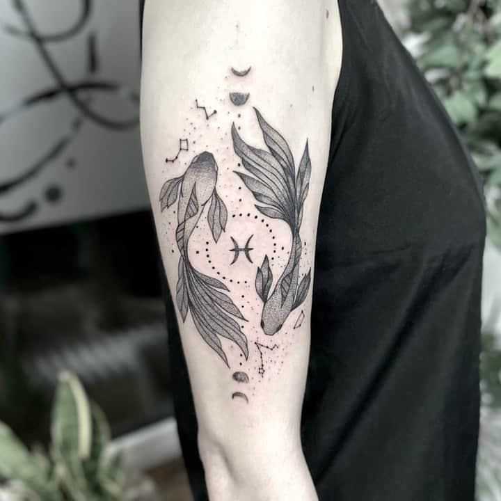 a black and white photo of a woman's arm with fish tattoos on it