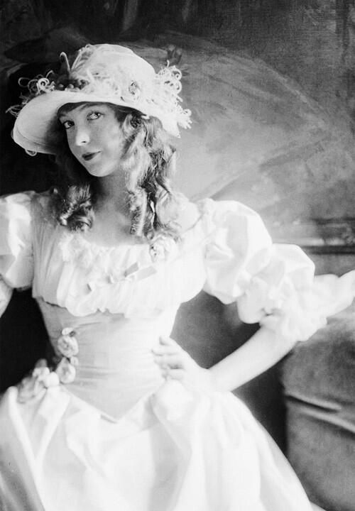 an old photo of a woman in a dress and hat