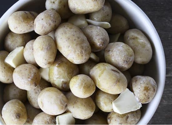 a white bowl filled with potatoes on top of a wooden table