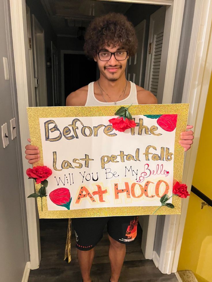 a man holding up a sign that says before the last petal fall will you be my dog at hoo?