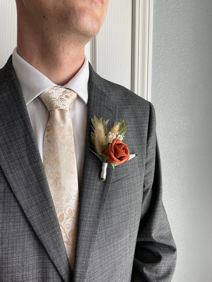 a man wearing a suit and tie with a boutonniere on his lapel