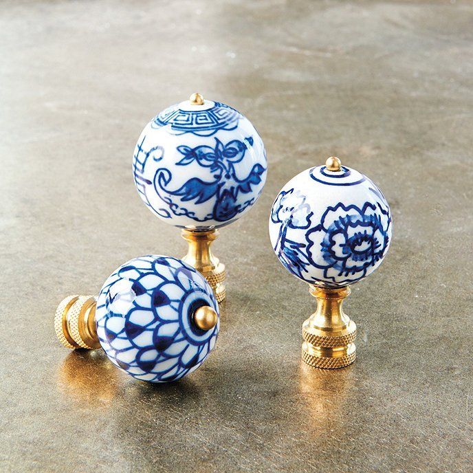 three decorative blue and white knobs on top of a counter with gold trimming