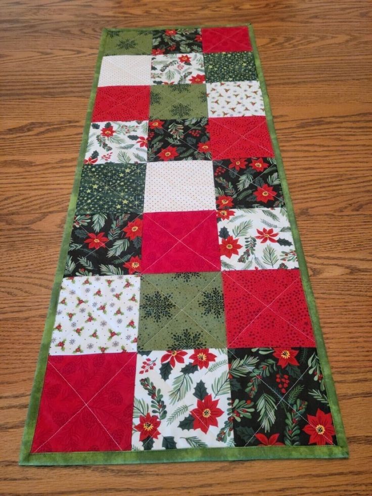 a quilted table runner with red, green and white squares on top of it