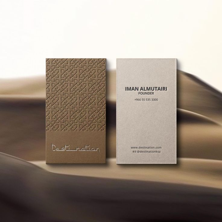 a business card sitting on top of a brown and white paper covered in an intricate pattern