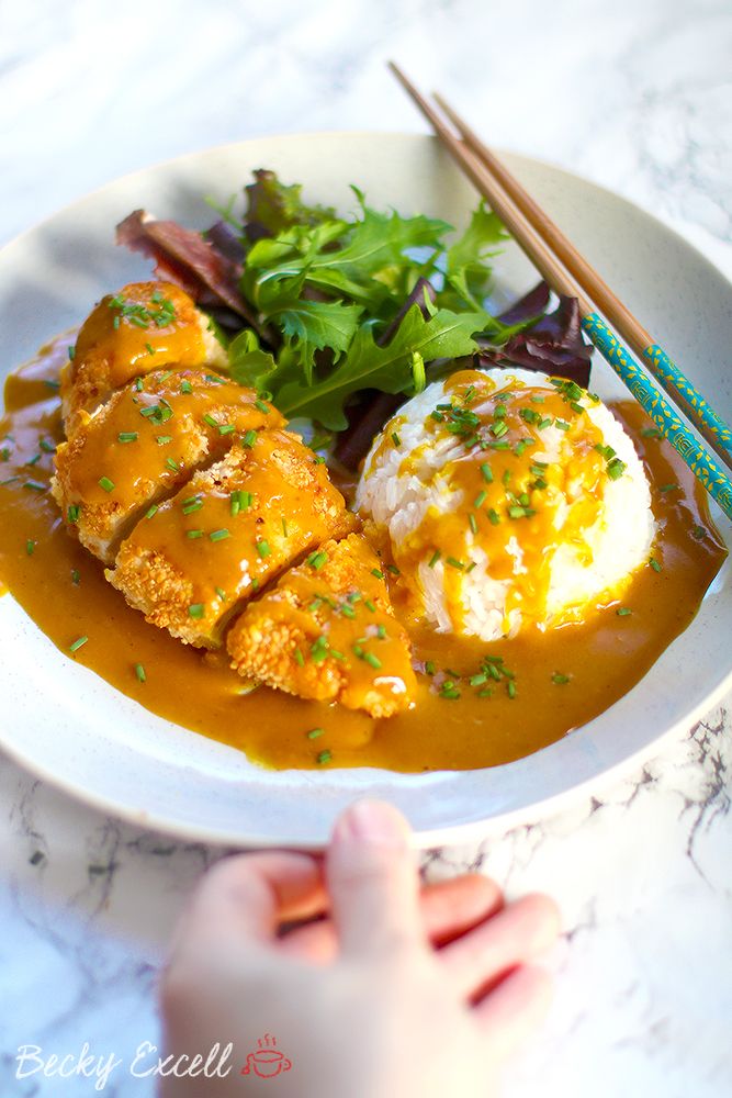 a white plate topped with meat covered in gravy next to chopsticks