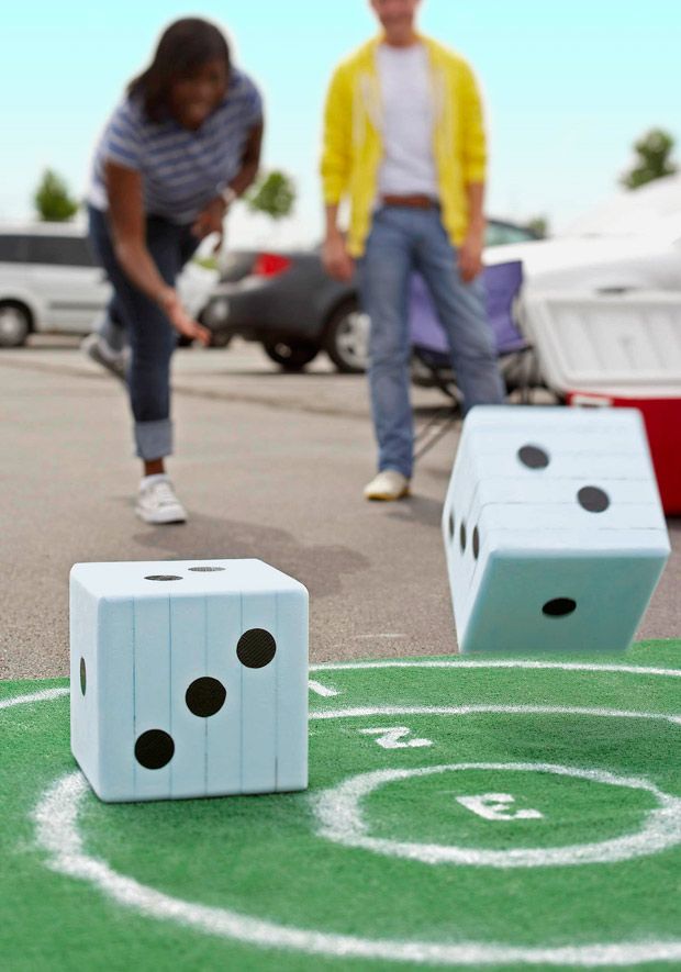 two white dices sitting on top of a green field next to people walking by