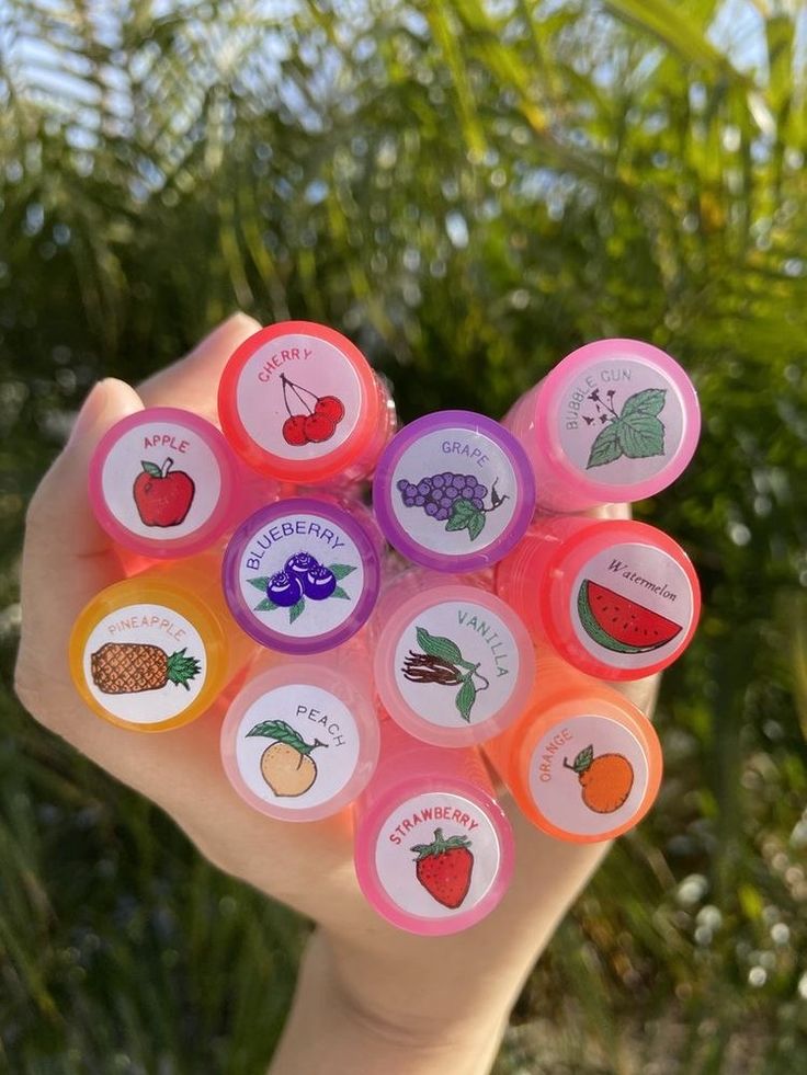 a person holding up six different colored frisbees in their hand with trees in the background