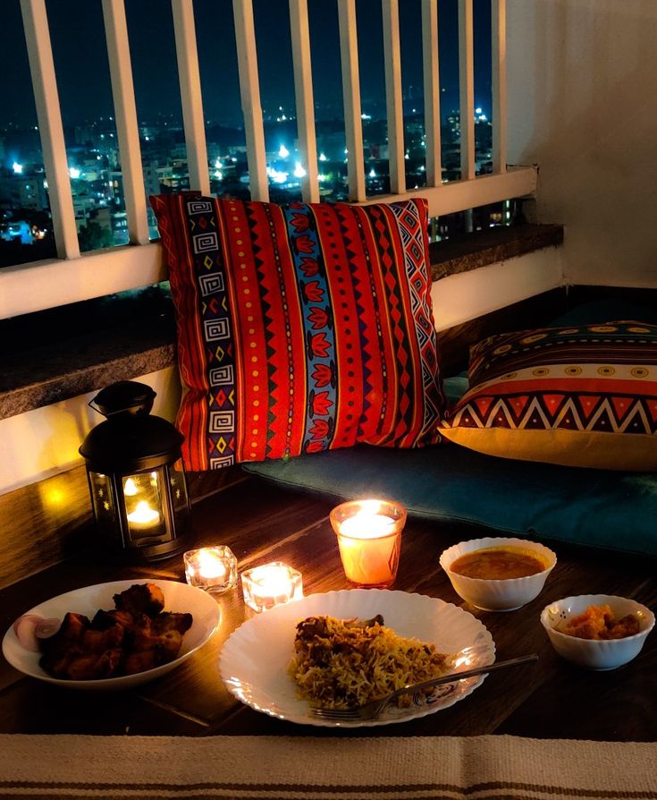 a table with food and candles on it in front of a window overlooking the city