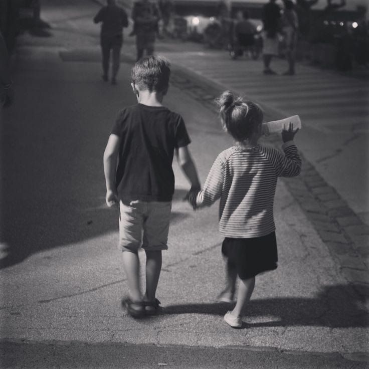 two children walking down the street holding hands