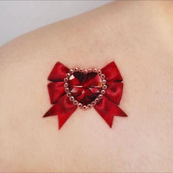 a woman's back with a red bow and heart shaped brooch on it