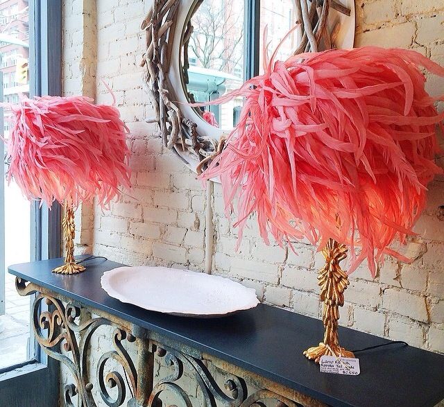 two pink feathers are sitting on top of a table next to a mirror and vase