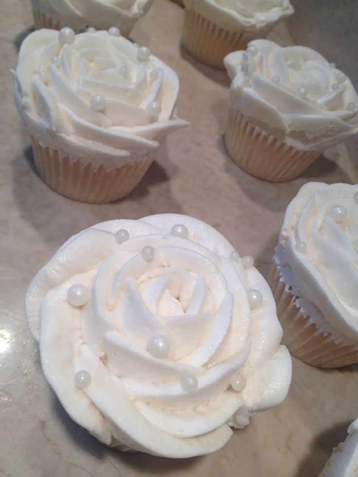 several cupcakes with white frosting and pearls on the top are arranged in a circle