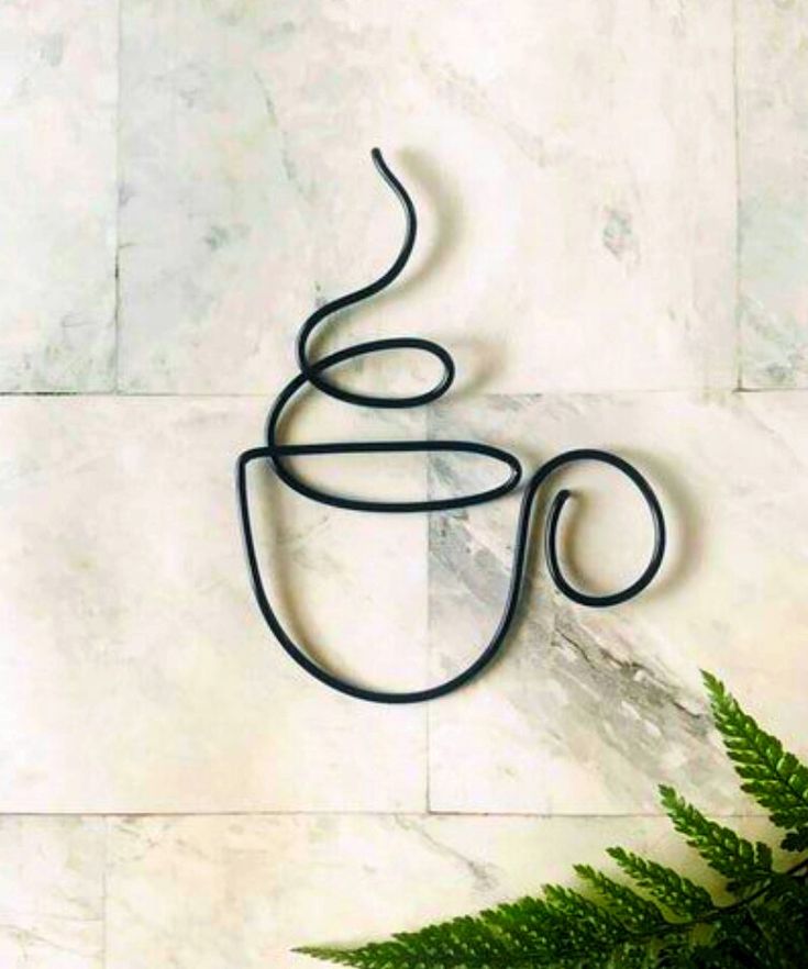 a coffee cup shaped like a snake sitting on top of a marble wall next to a green plant