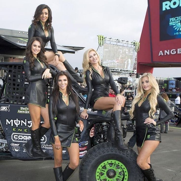 four beautiful women in black leather outfits standing next to an off - road vehicle