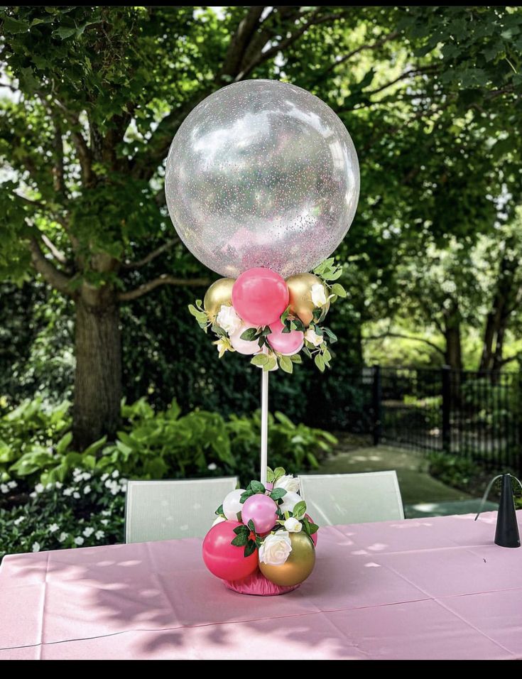 a table topped with a pink and gold centerpiece next to a giant bubble balloon