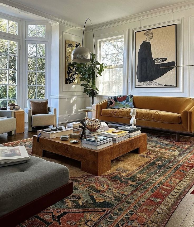 a living room filled with lots of furniture and large paintings on the wall above them