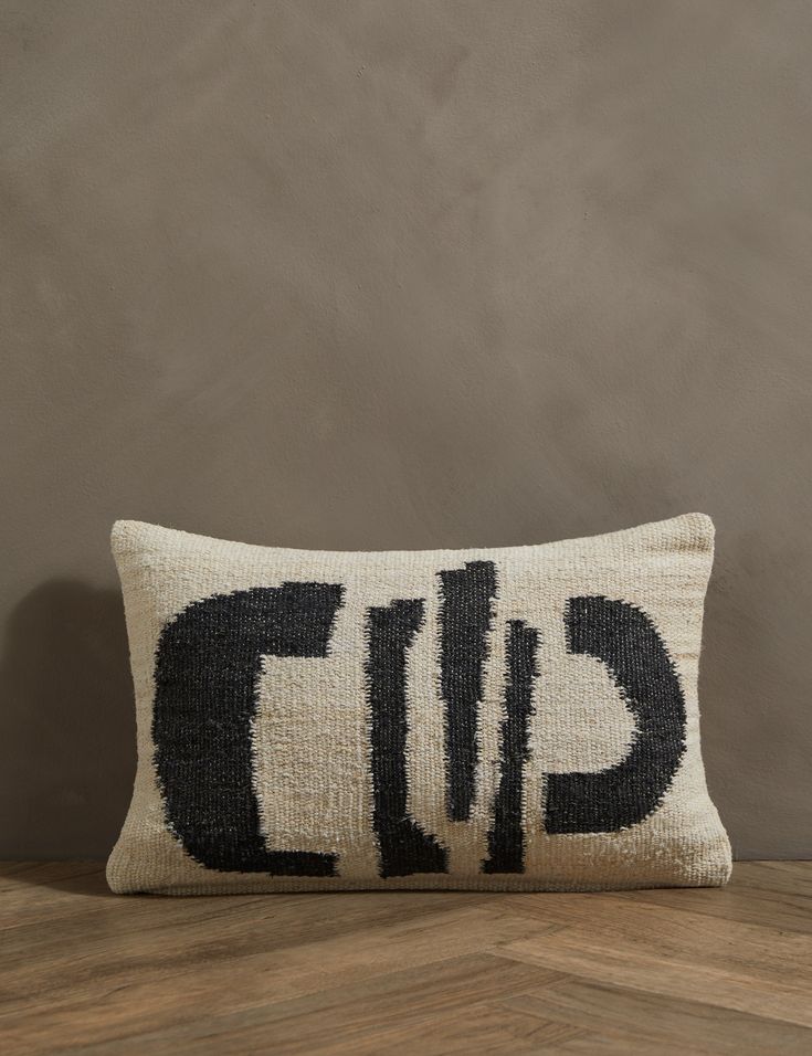 a black and white pillow with the word cut on it sitting on a wooden table