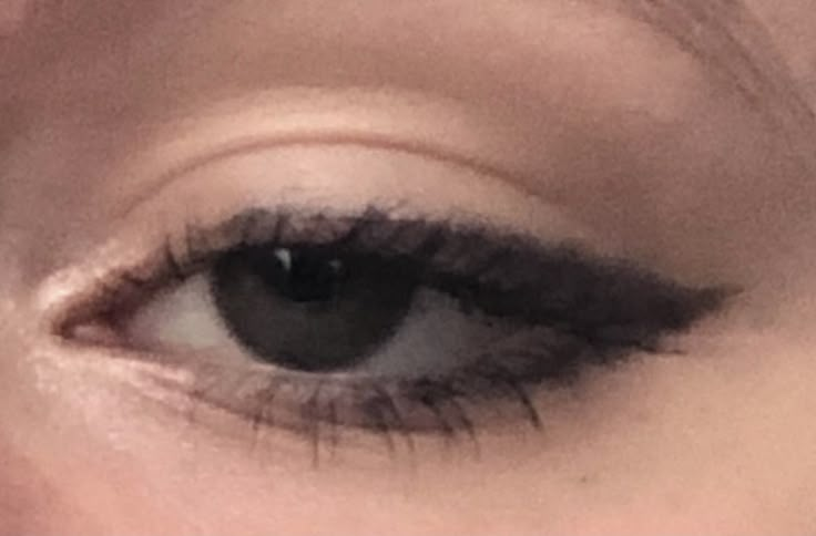 a woman's eye with long lashes and black liner on her eyeshadp