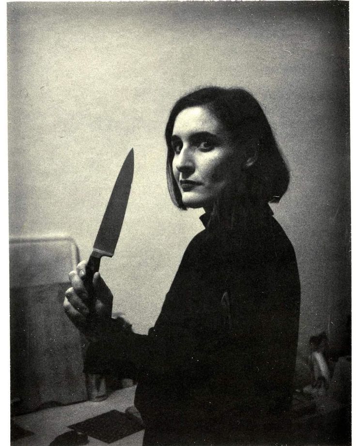 a black and white photo of a woman holding a knife