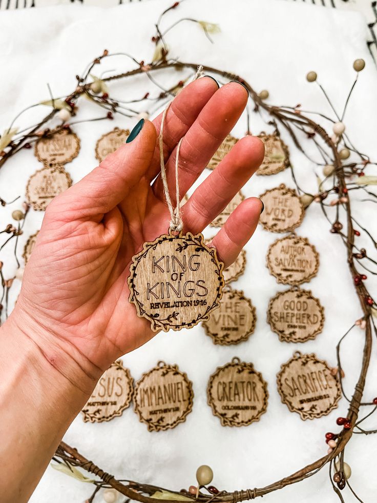 a hand holding a wooden ornament with the words king and queen on it