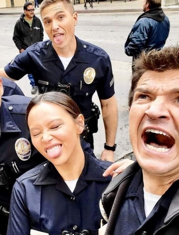 two police officers standing next to each other with their mouths open and people in the background