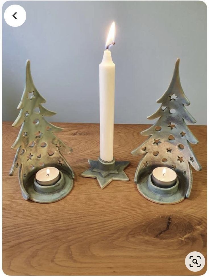 two metal christmas trees with candles in them