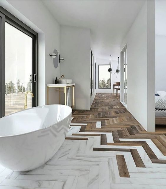 a large white bath tub sitting on top of a wooden floor next to a bed