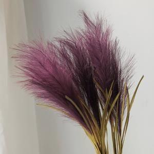 some purple flowers are in a vase on a white tablecloth and the background is off white