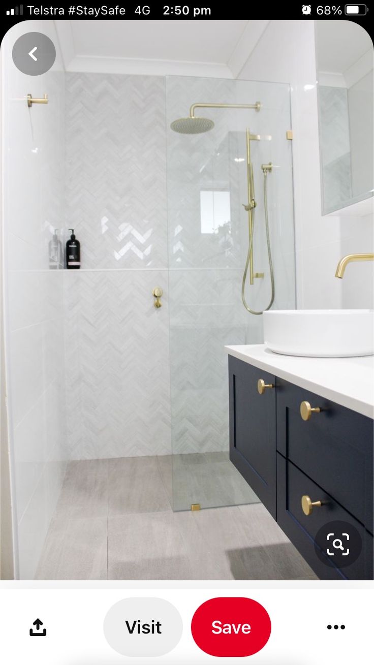 a bathroom with a walk in shower next to a white sink and blue cabinetry