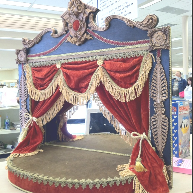 an elaborately decorated bed with red and gold drapes on it's sides