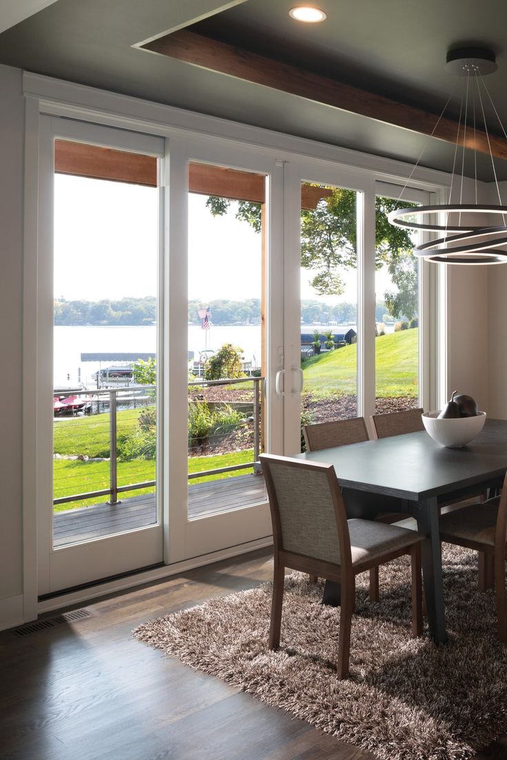 a dinning room table and chairs in front of sliding glass doors that look out onto the water