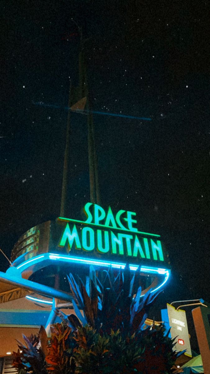 the space mountain sign is lit up at night