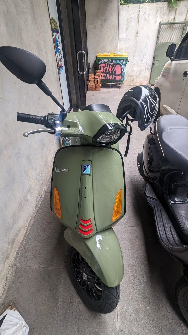 a green scooter parked next to a white car